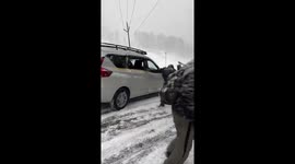 Cars and people slip down snow-covered hill in northern India
