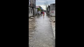 Locals and pet dog splash through continually flooded coastal town