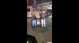 Tourist drags his suitcases behind scooter on way to airport