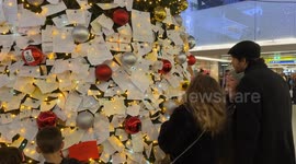 Travelers read wish cards that were hung by travelers on the decorated Christmas tree installed inside Termini Station during the Christmas season in Rome.
