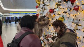 Travelers read wish cards that were hung by travelers on the decorated Christmas tree installed inside Termini Station during the Christmas season in Rome.