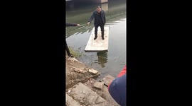 Man slips and falls into the water while riding a wooden board in Anhui, China