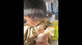 Child humorously pretends to nurse puppy in China