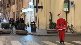 A person dressed as Santa Claus on skates enters Via del Corso among the people walking and above their heads the Christmas lights installed during the Christmas period in Rome.