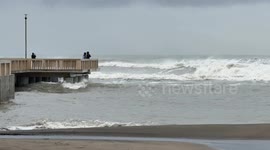 Some people on the Ostia pier look at the very rough sea on the coast of Lido di Ostia in Rome.