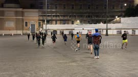 People train by running in Piazza del Popolo in the evening during the Christmas period with the guidance of a trainer who does a strange dance in Rome.