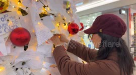 A girl sticks her wish note among others wish cards that were hung by travelers on the decorated Christmas tree installed inside Termini Station during the Christmas season in Rome.