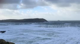 Strong wind whipping up big waves on the Cornish coast at Polzeath with Titan the Pug getting windswept as well