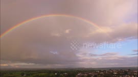 Drone footage of a vibrant rainbow at sunset