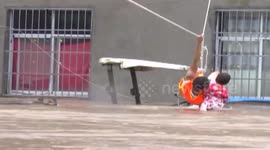 Firefighter helps child to cross flooded street