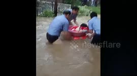 Police use foot basin to help child cross flooded street