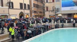 Tight shot of Piazza Fontana di Trevi as citizens and tourists with umbrellas watch the inauguration of the Trevi Fountain following the cleaning work for the Jubilee on a rainy December day in Rome.