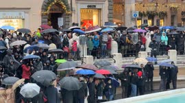 Tight shot of Piazza Fontana di Trevi as citizens and tourists with umbrellas watch the inauguration of the Trevi Fountain following the cleaning work for the Jubilee on a rainy December day in Rome.