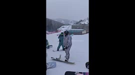 Snowboarding food vendor sells meat skewers while cruising down ski slopes