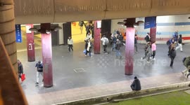A person sits at the exit as people exit the Anagnina metro station in the late afternoon on a winter's day in Rome.