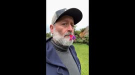Two Hummingbirds Visit Man Holding Flower