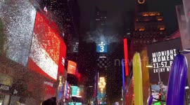 Times Square New Year’s Eve Ball drops, confetti falls, and couple kisses, and revelers dance