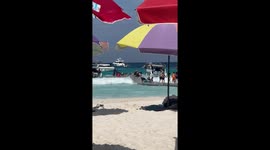 Tourists cling onto floating pontoon as wave hits shore