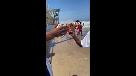 Wave washes away food while friends drink in Durban, South Africa