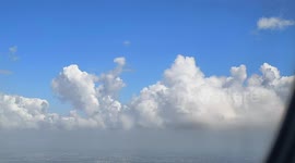 As I gazed out the airplane window, the sunny morning sun illuminated a breathtaking cloudscape. Soft, puffy cumulus clouds dotted the sky, resembling giant marshmallows. Towering clouds evoked medieval fortresses, while undulating stratus clouds resemble