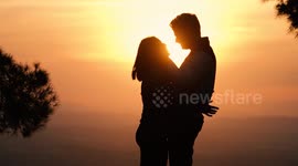 Silhouette of kissing couple against sunset at mountain top. Romantic scene of lovers kiss. Romance and activities for in love people in Saint Valentine's Day, Spain..