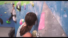 Woman climbing indoor safely in climbing wall. Bouldering sportswomen initiation climbers.