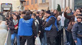 Tourists waiting to enter the Trevi Fountain stopped by two security personnel who regulate visitor access to the area in front of the Trevi Fountain in Rome.