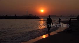 Silhouettes  of people and children relaxing and fishing on a beach at sunset, at Rayong, Thailand.