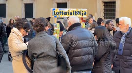 People buy an Italian lottery ticket from a street vendor near Via del Corso in Rome.