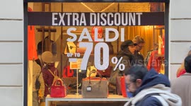 People inside a clothing store whose window displays the slogan ‘extra discount, sales up to 70%’ on the opening day of the winter sales in Rome.