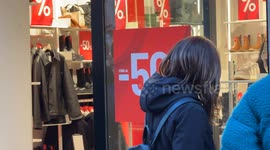 People leave a store displaying the promise of 50% discounts on the opening day of the winter sales in Rome.