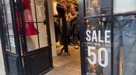 People in a clothing store displaying the promise of 50% discounts on the opening day of the winter sales in Rome.