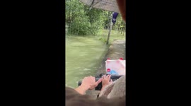 Motorcycle rider carefully negotiates path swamped with floodwater
