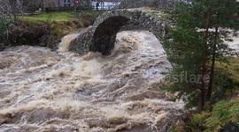 River in spate, flooding after heavy rain in carrbridge, Scotland. 300 year old bridge.