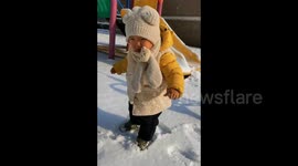 Toddler steps out onto snow for first time and cries at crunching sound