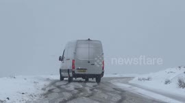 Determined delivery driver skids sideways across icy road in Devon as snow falls