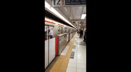 Tokyo subway entering station with a lot of people waiting in the morning.