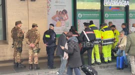 Emergency medical personnel pick up and carry away a drunk person outside Termini Station in Rome.