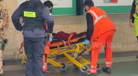 Emergency medical personnel pick up and carry away a drunk person outside Termini Station in Rome.
