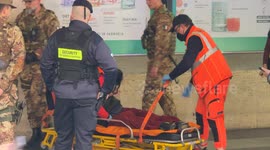 Emergency medical personnel pick up and carry away a drunk person outside Termini Station in Rome.