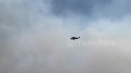 Helicopter drops water on Palisades Fire raging in California