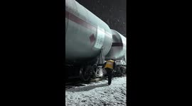 Railway worker checks train in heavy snow for safe oil transport