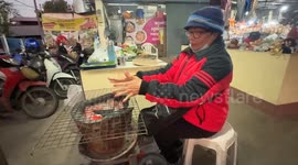 Market stall vendors warm their hands above hot coals amid cold spell in northern Thailand