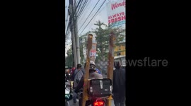 Cyclist balances five boxes on his head to make a delivery in rush hour traffic