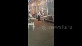 Caring security guard feeds hungry stray cat outside cafe