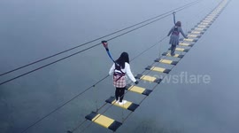 Tourists walk along terrifying rope bridge above gorge in Vietnam
