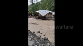 Flood surges near riverside homes in the Philippines