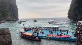 Tourists sway as strong waves hit boats and pontoon on Thai island