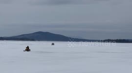 Volvo car and Ski-Doo snowmobile racing on West Cove of Moosehead Lake in Maine