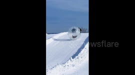 Locals climb into inflatable balls to roll down snow-covered hill in China